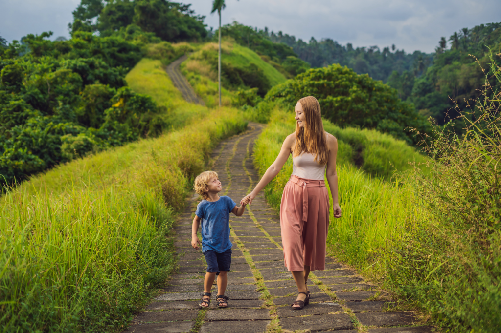 Mother and son happily walk down the lush green Campuhan Ridge