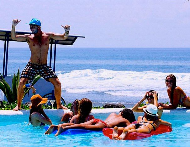 DJ Fisher entertaining guests at the Hotel Komune Bali opening party pool in 2012, with the Keramas surf break behind